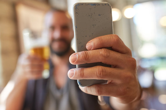 close up of man with smartphone and beer at pub