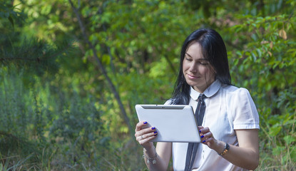 Fototapeta premium Young woman standing in the woods with her white tablet