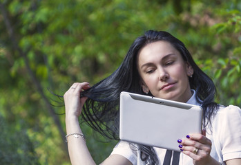 Young woman standing in the woods with her white tablet