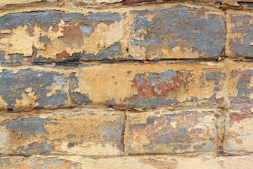 Old brick wall with remnants of yellow and red paint