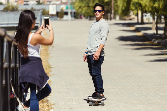 Two skaters using mobile phone in the street.
