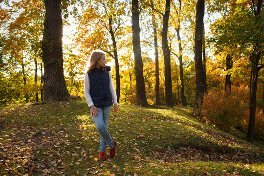 Cute Teenager girl walks in Autumn park. Sunny day, selective focus