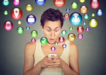 Shocked man using smartphone application icons flying out of cellphone