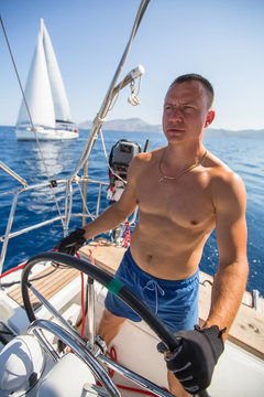 Yachtsman skipper during race, on his sailing yaht boat on the sea.