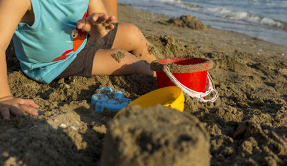 baby playing with sand toys on beach