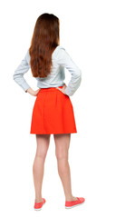 back view of standing young beautiful  woman in dress. girl  watching. Rear view people collection.  backside view of person.  Isolated over white background. A woman in a red skirt standing with