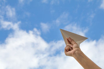 hand holding paper plane on sky background