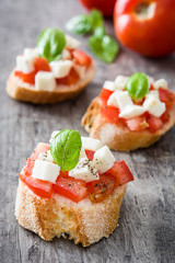 Caprese salad bruschettas on wooden table

