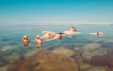 Man float meditating in water Dead Sea. Tourism recreation, healthy lifestyle concept. Copy space. Peaceful meditation