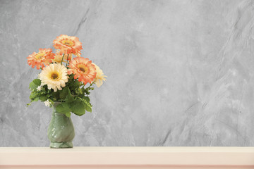 flower in vase on wooden table with cement wall