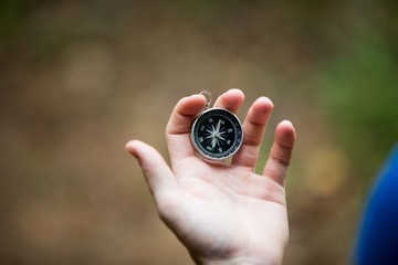 Hand holding compass in forest