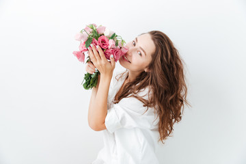 Happy cute young girl smelling flowers