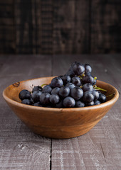 Fresh grapes in wooden bowl on wooden background