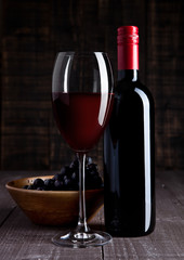 Bottle and glass of red wine with grapes in bowl