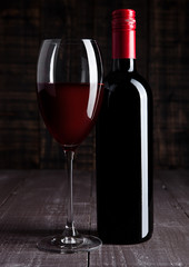 Bottle and glass of red wine on wooden board