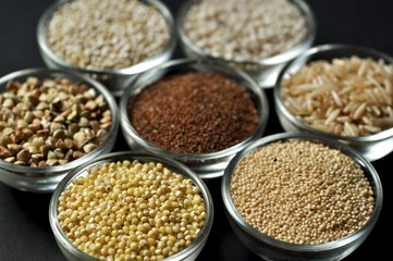 Gluten-free grains in glass bowls on black background close-up