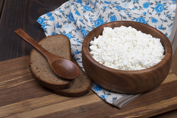 fresh cottage cheese in a woden plate and bread on wooden background in countryside style