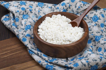 fresh cottage cheese in a woden plate on wooden background in countryside style