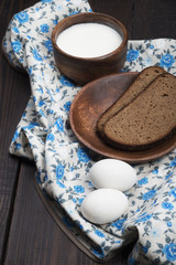 fresh bread, eggs and a cup of milk cream on a wooden background and towel in oriental style