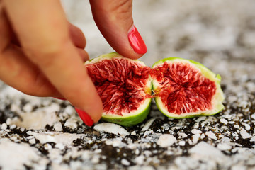 Fototapeta na wymiar Female fingers with fig fruit