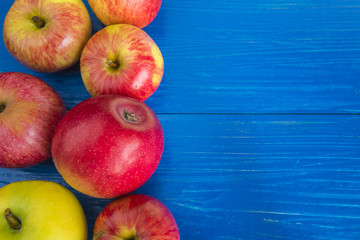 Red and yellow apples on a blue wooden background with copy space