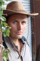 Portrait of serious young cowboy with hat looking away isolated on textured gray background