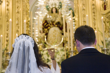 Bride and groom in front of Virgin Mary image during a Catholic mass, Seville, Spain