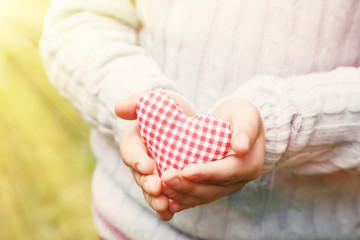 Child hand holding red heart