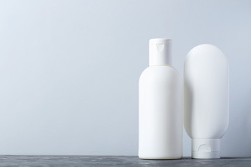 White cosmetic bottles on a grey table