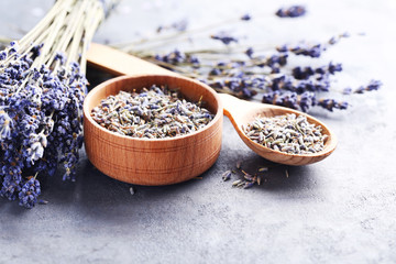 Lavender flowers in bowl and spoon on grey table