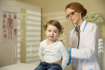 Cute little girl and doctor. Pediatrician woman examining cute little girl with stethoscope. Kid looks healthy and happy