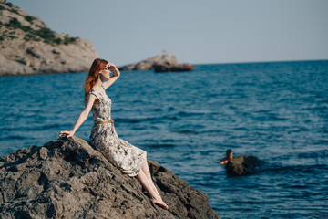 woman on the beach, sitting on a rock Woman, long hair in dress