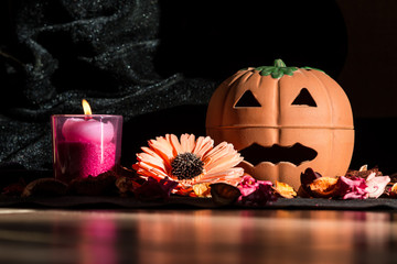 halloween pumpkin with dried flowers potpourri and tealight on black background - front view