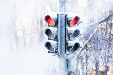 Frozen traffic lights on the winter street. Green and red light. Snow, frost and steam. 
