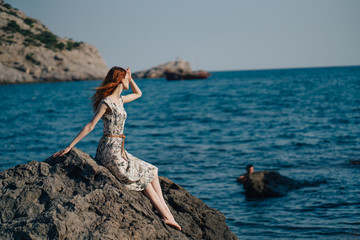 woman on the beach, sitting on a rock Woman, long hair in dress