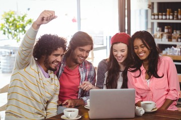 Group of friends using laptop while having cup of coffee