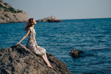 woman on the beach, sitting on a rock Woman, long hair in dress