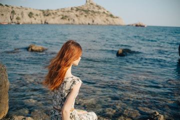 Fototapeta na wymiar woman on the beach, sitting on a rock Woman, long hair in dress