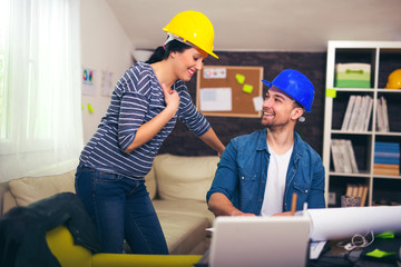 Smiling architect looking the architectural plans in office