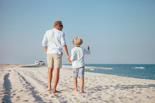 Father with son walk on deserted sea beach