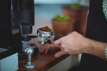Waiter holding portafilter filled with ground coffee