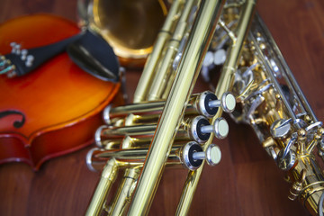 Detail close up of a trumpet, saxophone and violin still life on a wood surface