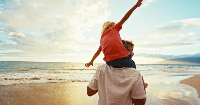 Happy father and son playing on the beach at sunset