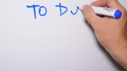 Hand writing a TO DO LIST with blue marker on white board