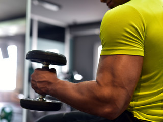 Muscular bodybuilder guy doing exercises with dumbbells