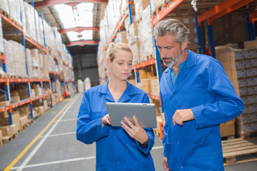 Male and female warehouse workers looking at tablet