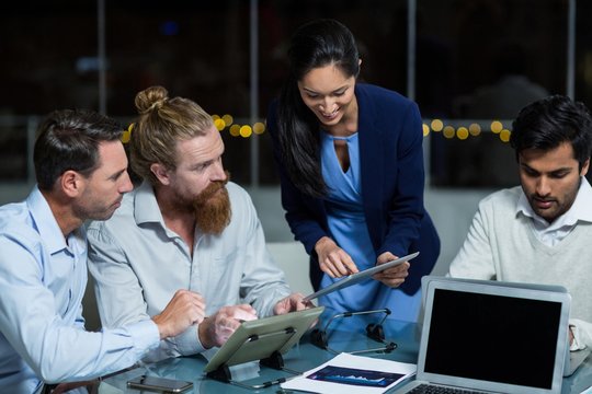 Businesswoman discussing with colleagues over digital tablet