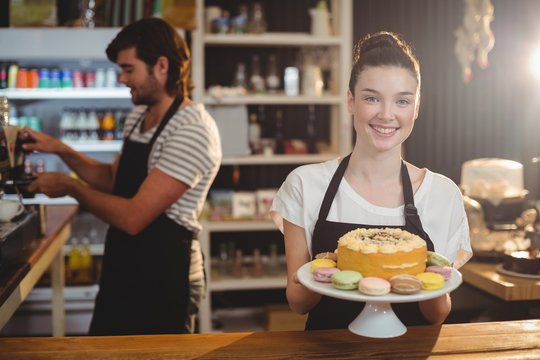 Portrait of waitress holding dessert on cake stand