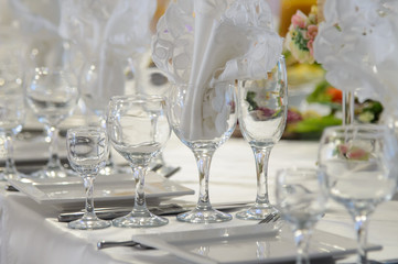 The gala dinner. Clear wine glasses on white festive table. The Banquet hall serving of food and Cutlery. 