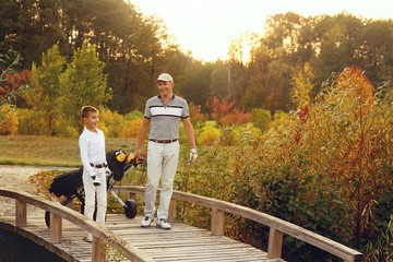 Father with son golfers are walking enjoying autumn lanscape